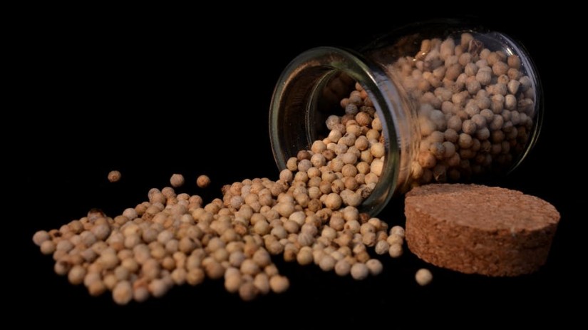 Spilled chickpeas from an overturned glass jar with a cork lid.