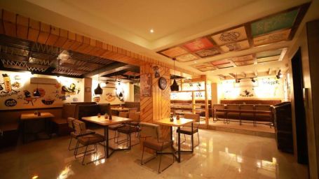 a warmly lit interior of chipotle restaurant furnished with marbled flooring and trendy decors - Click Hotel Capital House, Patna