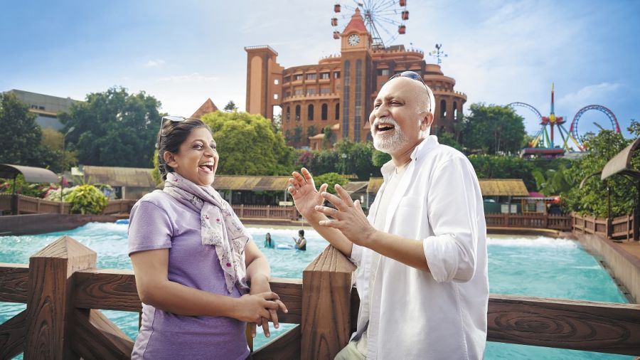 old couple in front of the Skywheel  and Wavepool panorama