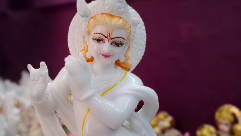 a white idol of lord Krishna with golden carvings