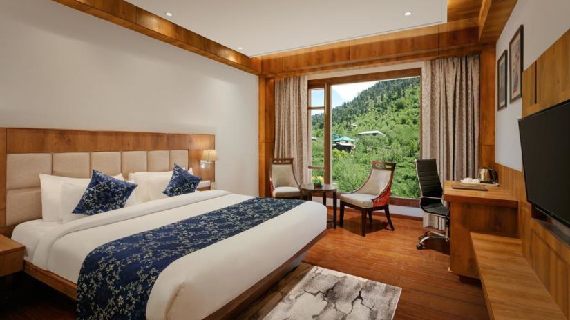 A luxury suite with a king size bed and wooden floorings at The Orchid Hotel, Manali