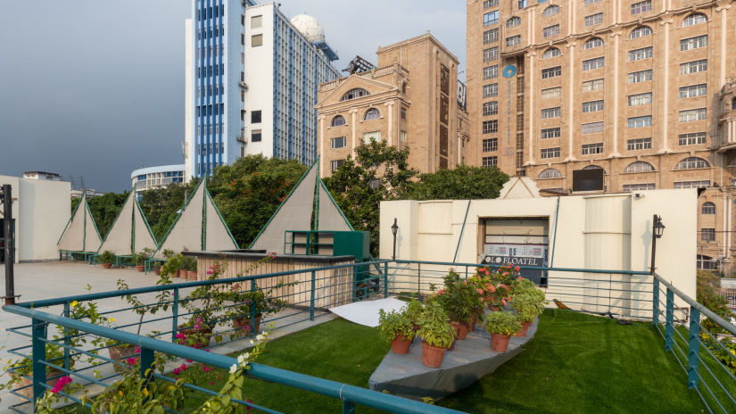 the lawn area with green grass and a boat shaped thing with potted plants on it at Polo Floatel Kolkata