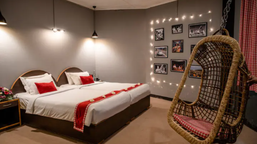 Modern bedroom with twin beds, stylish swing chair, and wall art display - at Woodstock Cafe BnB