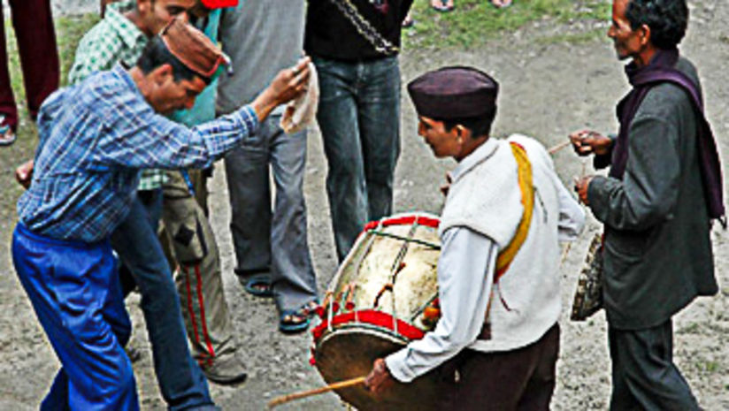 An image of musicians playing the drum and a group of men dancing during Wedding celebration