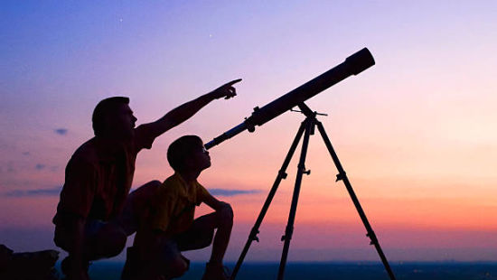 Two people engage in stargazing using a telescope against a twilight sky, pointing towards the heavens in search of celestial wonders.