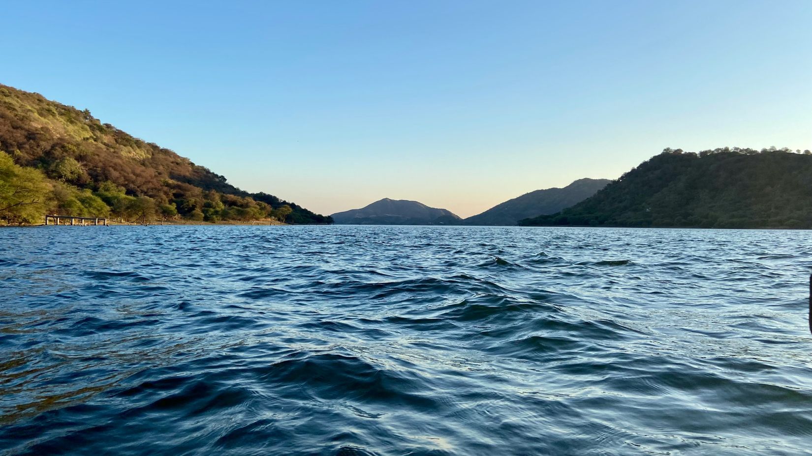 an overview of Jaisamand Lake in udaipur with mountains in the background