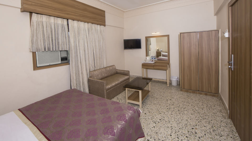 room with king size bed and sofa in dadar at hotel bawa regency