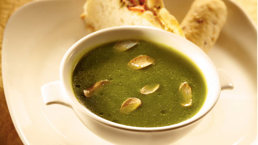 A bowl of green soup with dry fruits