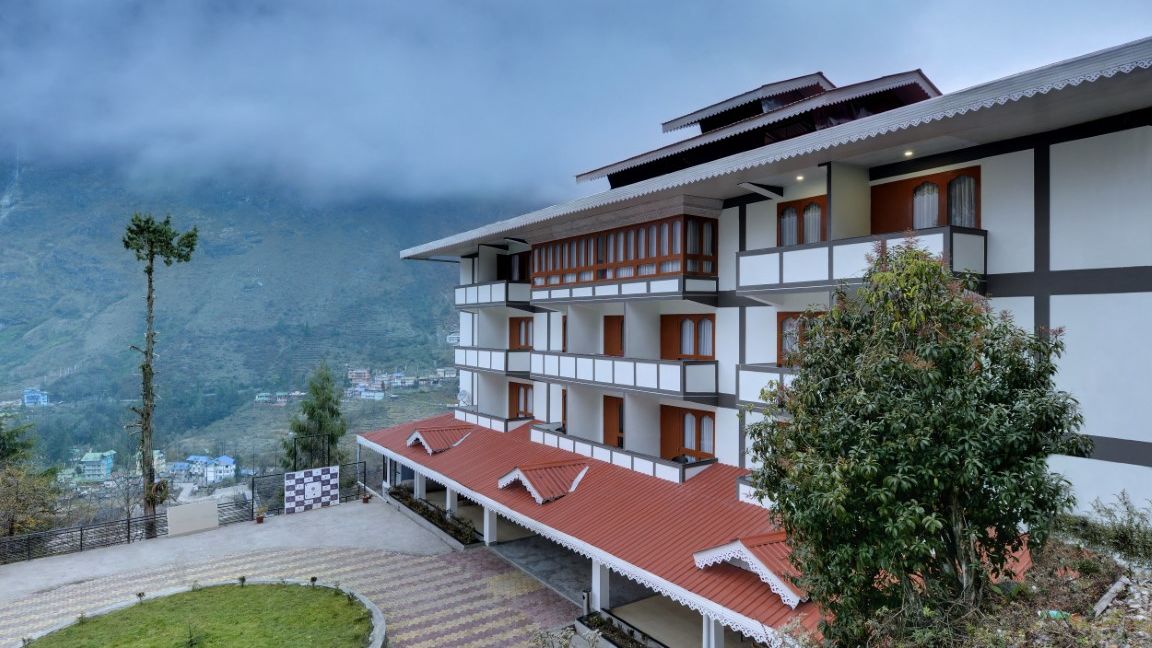 A long shot of a building beside mountains | Sumi Yash Shree Hotels & Resorts