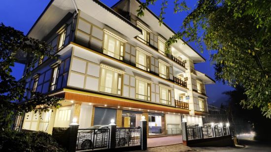 A low high angle of facade of a well-lit 3-storey building at night | Sumi Yash Shree Hotels & Resorts