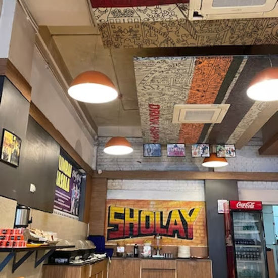 alt-text Hotel dining space with buffet counters and a Sholay signboard, vintage decor overhead.