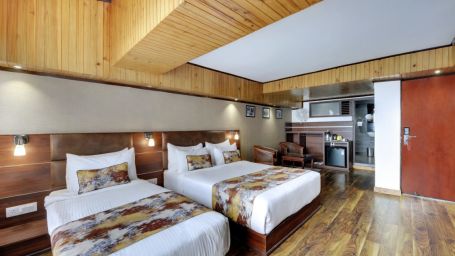Deluxe triple bedroom with one large bed and one single bed with a wardrobe beside them - Yashshree mall Road, Darjeeling