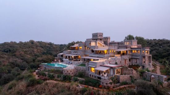 Facade image of Chunda Shikhar Oudi Jaipur placed on a small hill with forest cover