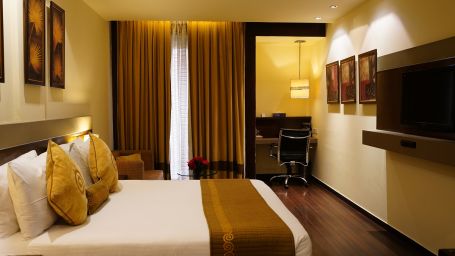 Club Room decked with a comfy bed, a television and a work desk at Shervani Nehru Place, New Delhi