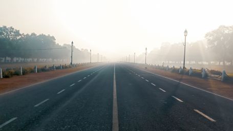 A road leading the india gate with mist cover in the background