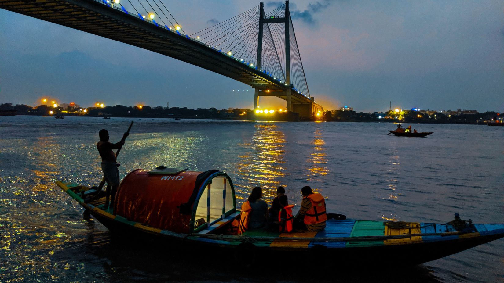 Howrah bridge with a boat passing by in Hooghly river