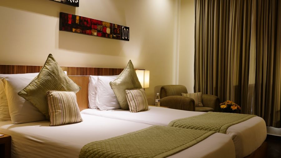Standard Room featuring twin beds with green duvets and pillows at Shervani Nehru Place, New Delhi