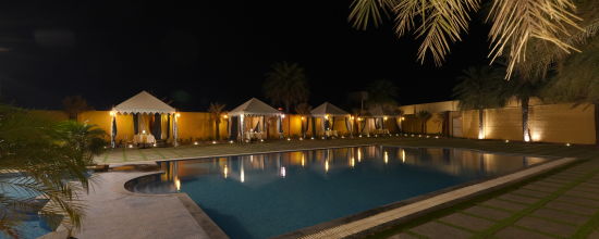 alt-text Side view of the The Palm Pool at night and tent seating at The Garden Ananta Elite Rajkot 2