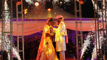 Swosti Chilika Resort - Image of a couple dressed in traditional Indian attire standing on a stage that has fireworks going off on the edge