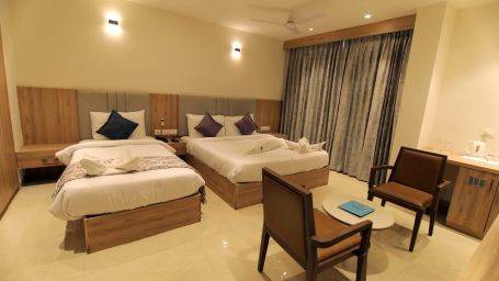 Well lit room at Hotel Mumbai House Express, Udaipur with twin beds and seating arrangement