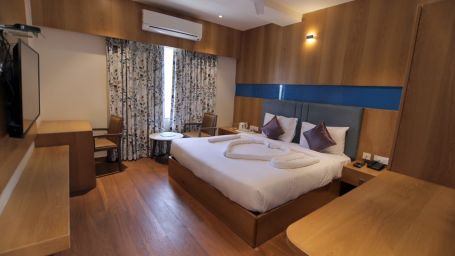 Room at Hotel Mumbai House Express, Udaipur with a double bed and a television