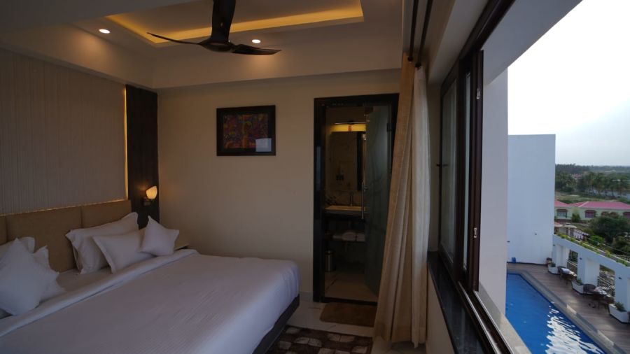 a double bed with a massive glass window opposite the bed in one of the rooms - Shanti Seaview Resort & Spa