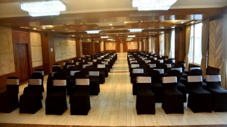 A Chamber Hall in Shimla with rows of black clad seats - The Orchid Hotel Shimla