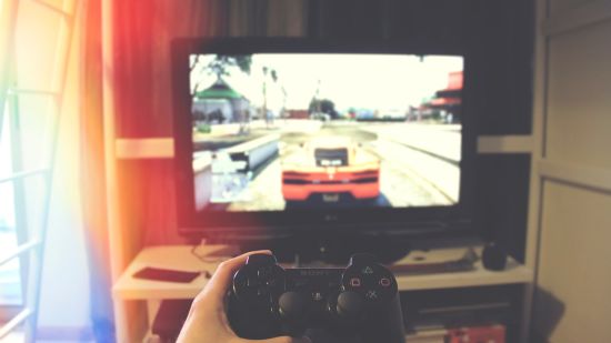 A point-of-view shot of a person holding a controller and playing a car race game on a play station