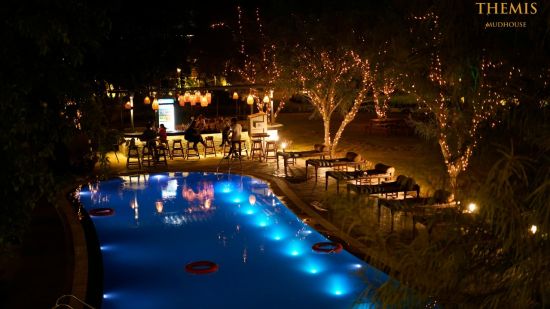 Well-lit swimming pool at night at inflated trampoline surrounded by trees at Themis Mudhouse - A Nature's Retreat Resort & Wellness