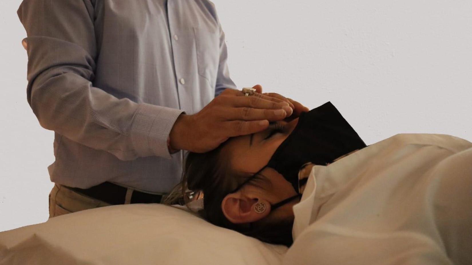 Yo1 Longevity and Health Resorts - Image of a man gently placing his palm on a person s forehead as they close their eyes