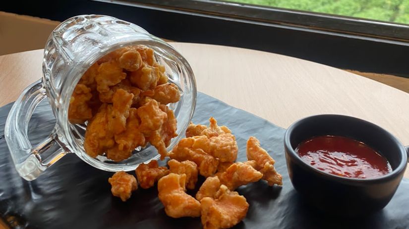 An enticing view of fritters spilling over to the table next to a ketchup dip