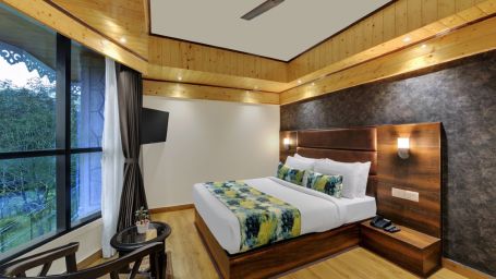 An image of Sumitel Queensyard premium room with king size bed, ceiling fan and an expansive window