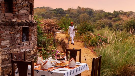 outdoor seating for dinner with chairs and tables placed next to nature - Chunda Hotels