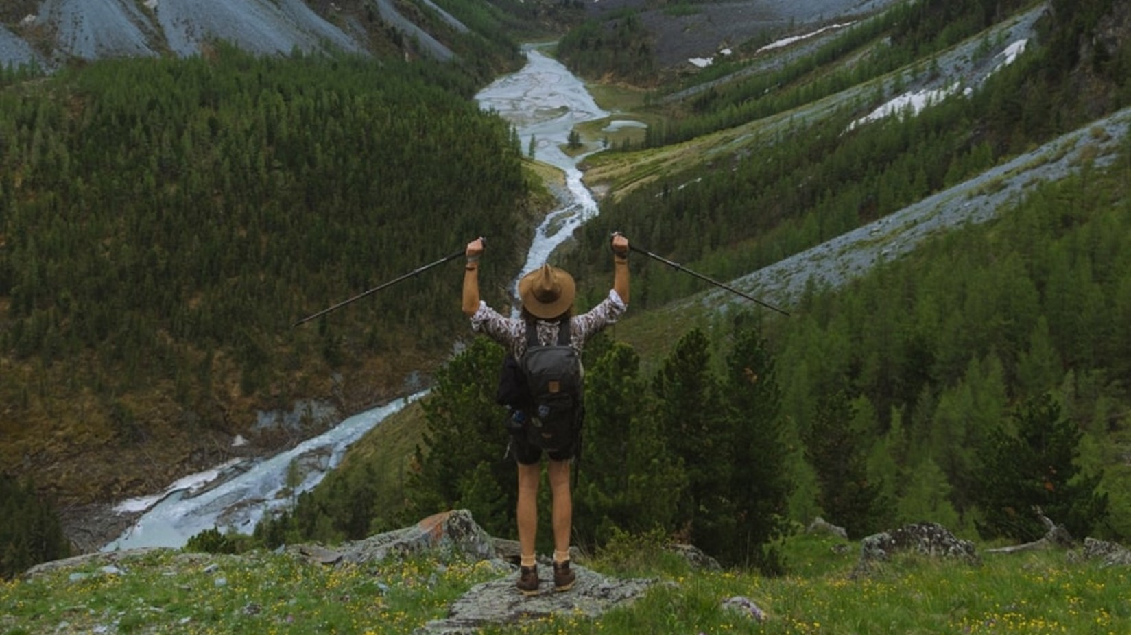 a hiker standing with arms raised amidst nature