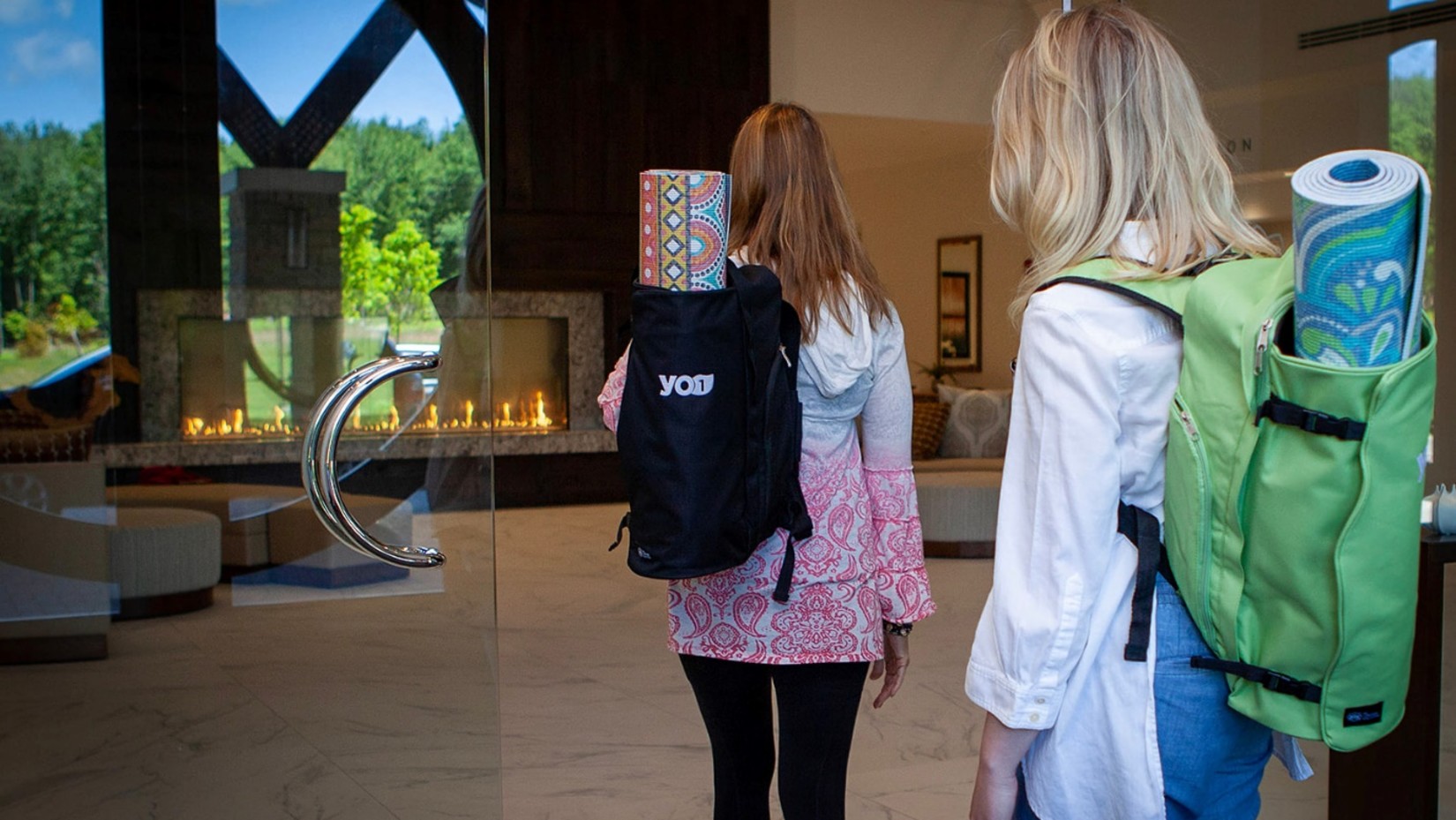 Two women enterting a building with yoga mats in their bag