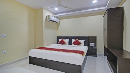 A hotel room featuring a double bed, storage cabinet, air conditioning, wardrobe and a simple design.