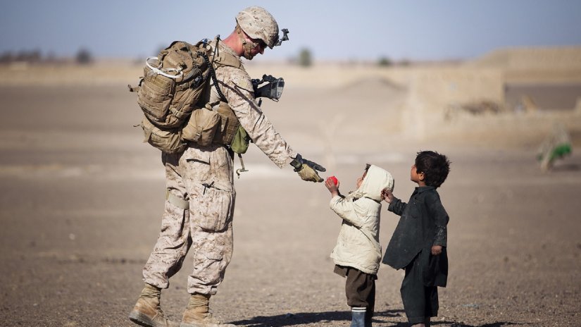 two children gifting flower to a soldier