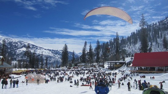 A man on a parachute on a snowy valley at Solang Valley Summit 