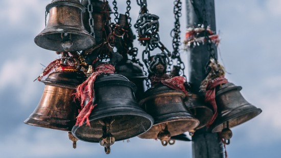 Temple bells with red sacred thread surrounding them