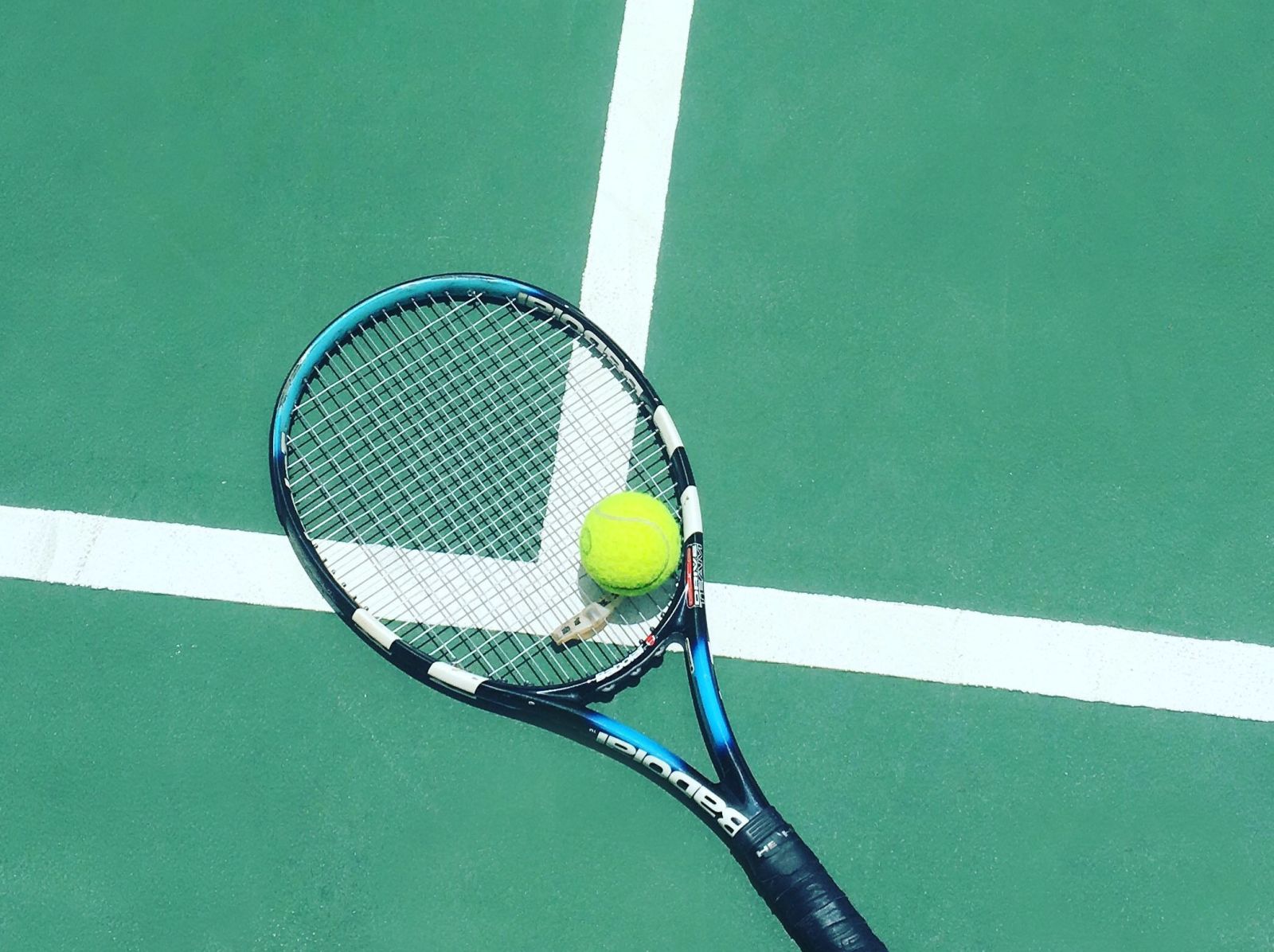 a tennis racket and ball kept on a court