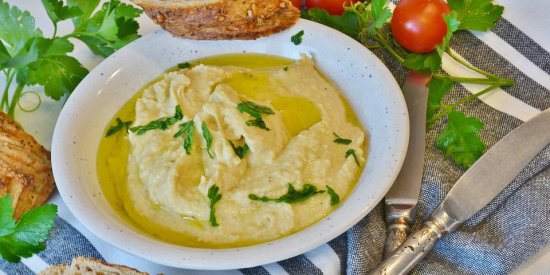 hummus served on a plate along with a loaf of bread