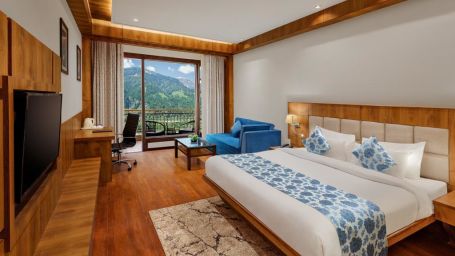 Room with a commodious bed and wooden furnishings overlooking lush greenery