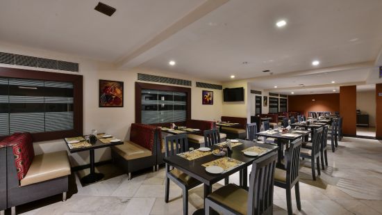 An elegantly set restaurant interior with booths and tables - Click hotels Yuvraj, Surat