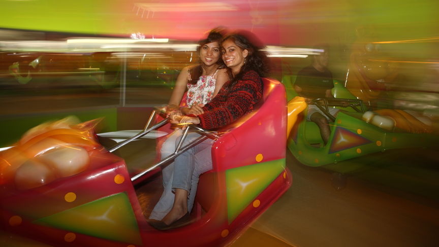 blurred image of two women riding on a dancing car ride