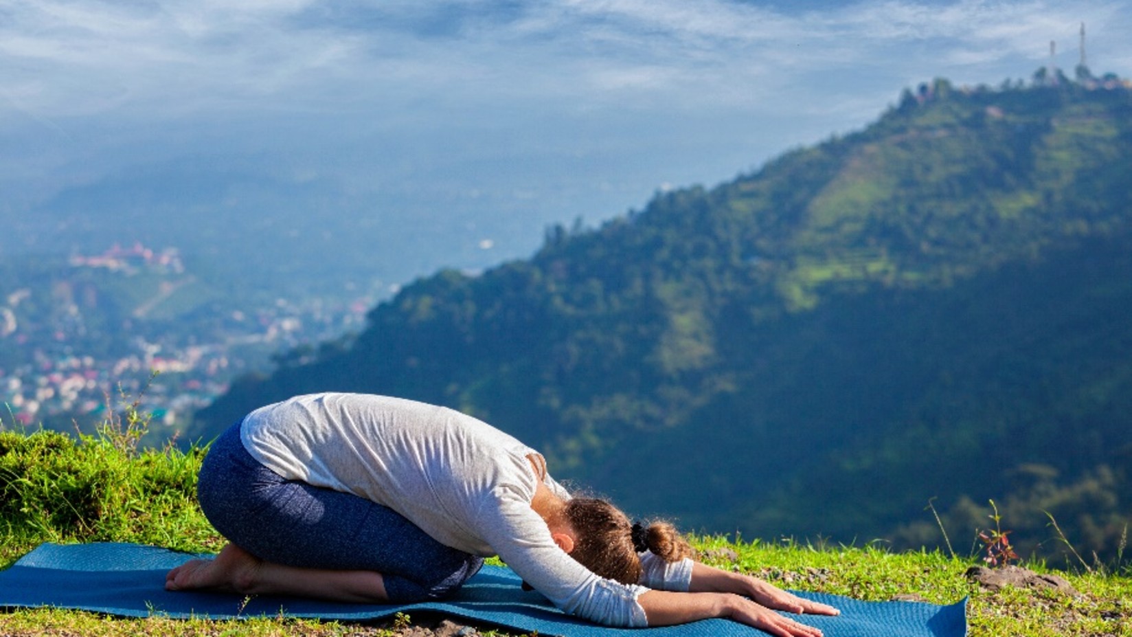 a woman doing yoga by a mountain