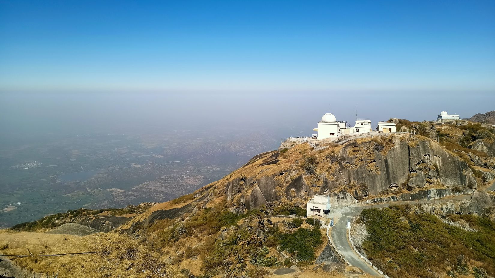 an aerial view of Mount Abu with a building on the top and blue sky in the background