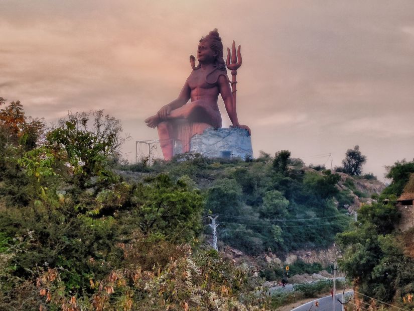 An image of a hindu idol in the background with trees covering