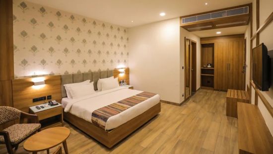 executive room at Comfort Resort, Morbi displaying elegant golden prints on white wall with a bed placed in it