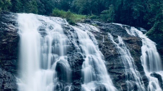 view of a gushing waterfall in Coorg surrounded with lush greenery