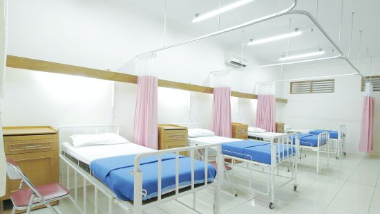 three hospital beds in view with white walls and bright lighting